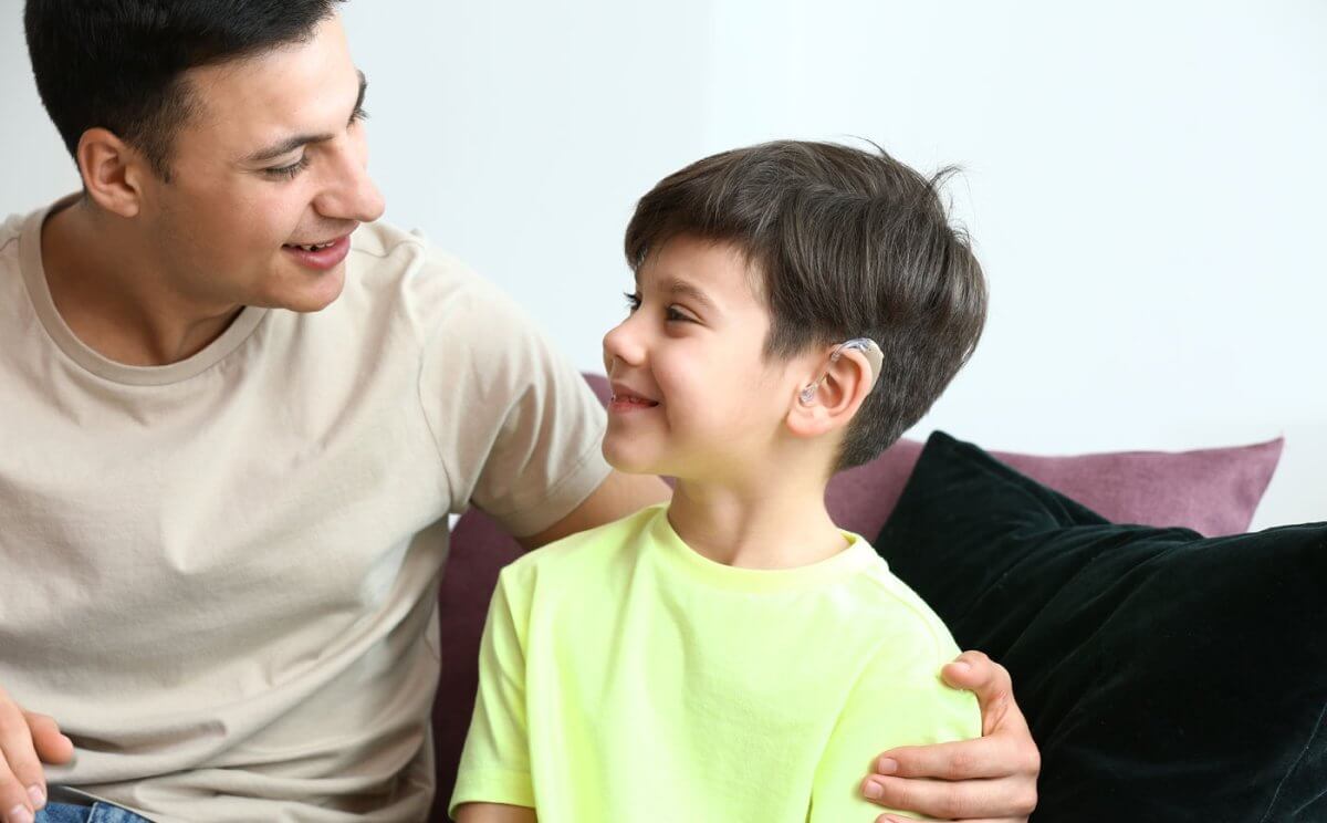 father talking to son wearing hearing aids