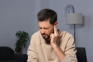 man suffering ear pain from tinnitus
